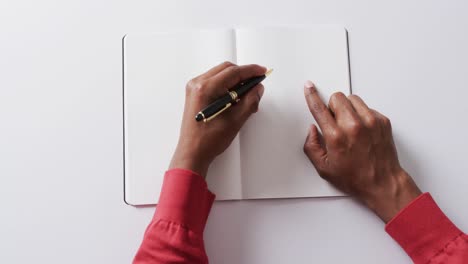 close up of hand writing with pen on book with copy space on white background in slow motion