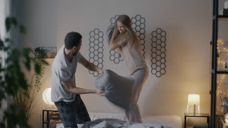 couple having a pillow fight in bedroom