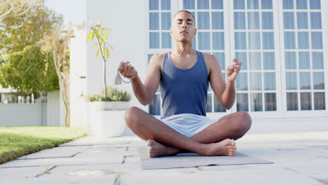 Focused-biracial-man-practicing-yoga-meditation-in-sunny-garden,-slow-motion