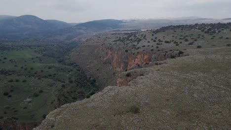 Drone-Aéreo-Sobrevuelo-Terreno-Rocoso-Que-Revela-El-Valle-Verde-Debajo,-Israel,-Nahal-Amud