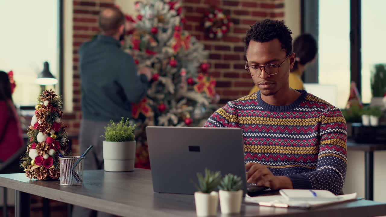 Company employee using laptop in christmas decorated office