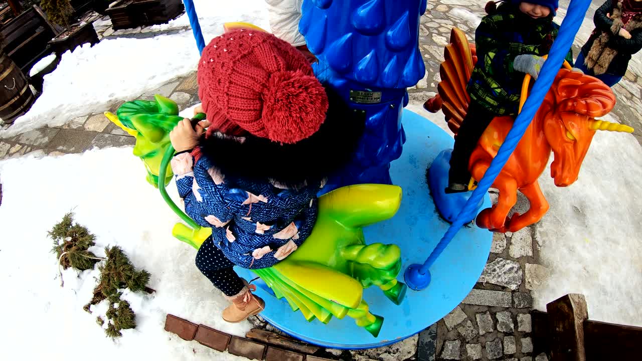 행복한 어린 소녀가 마리-고-라운드에서 승차를 즐기고, 귀여운 유아가 놀이터에서 재미를 느끼고, 느린 동작