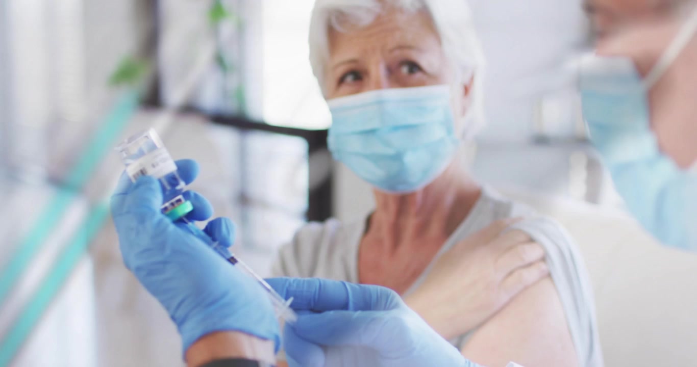 Clinician flipping vial, drawing vaccine for patient, graphics overlaying guiding syringe injection