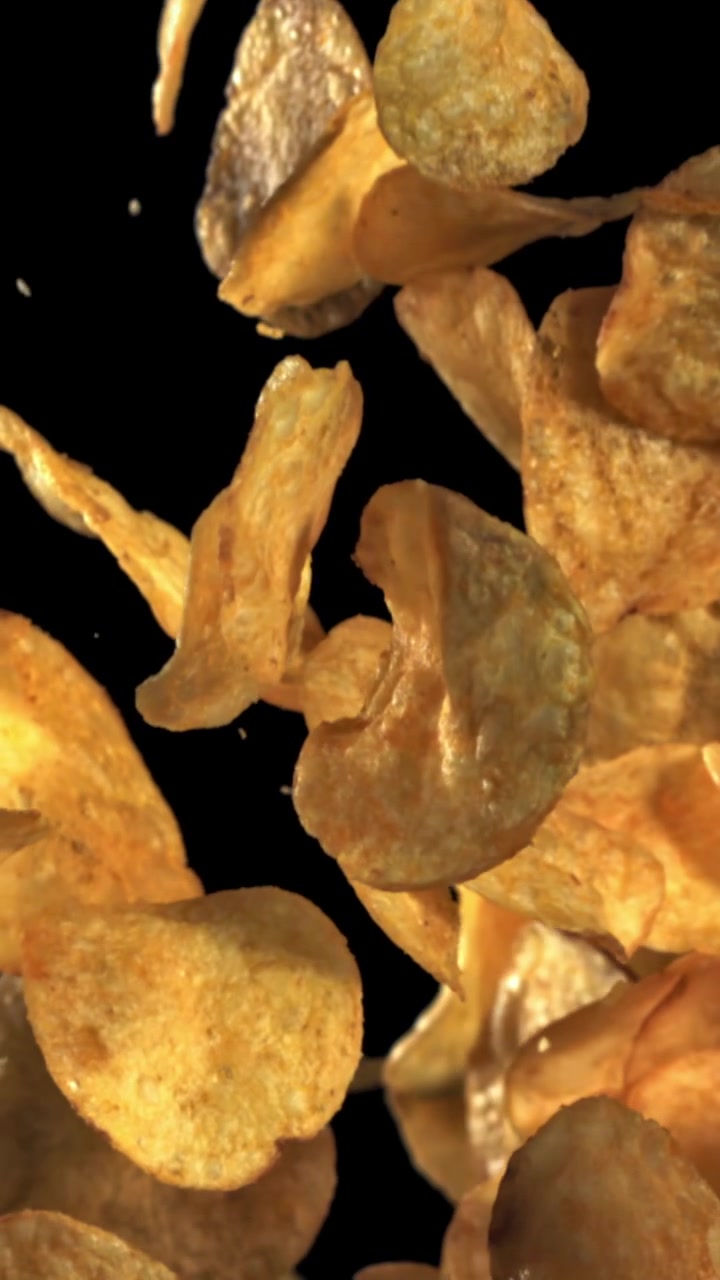 Crispy Potato Chips Falling in Slow Motion Against a Black Background