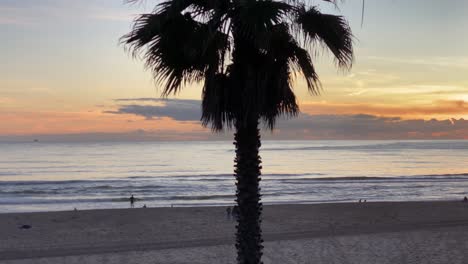 Tourist-carrying-surfboard-running-to-the-sea,-surfing-with-amazing-sunset-in-middle-of-clouds