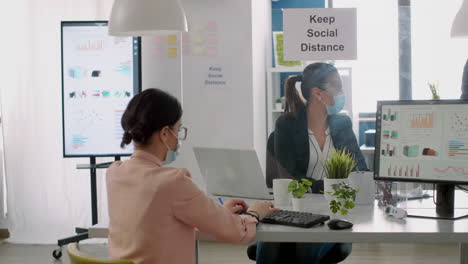 group of business people with face masks working in new normal company office