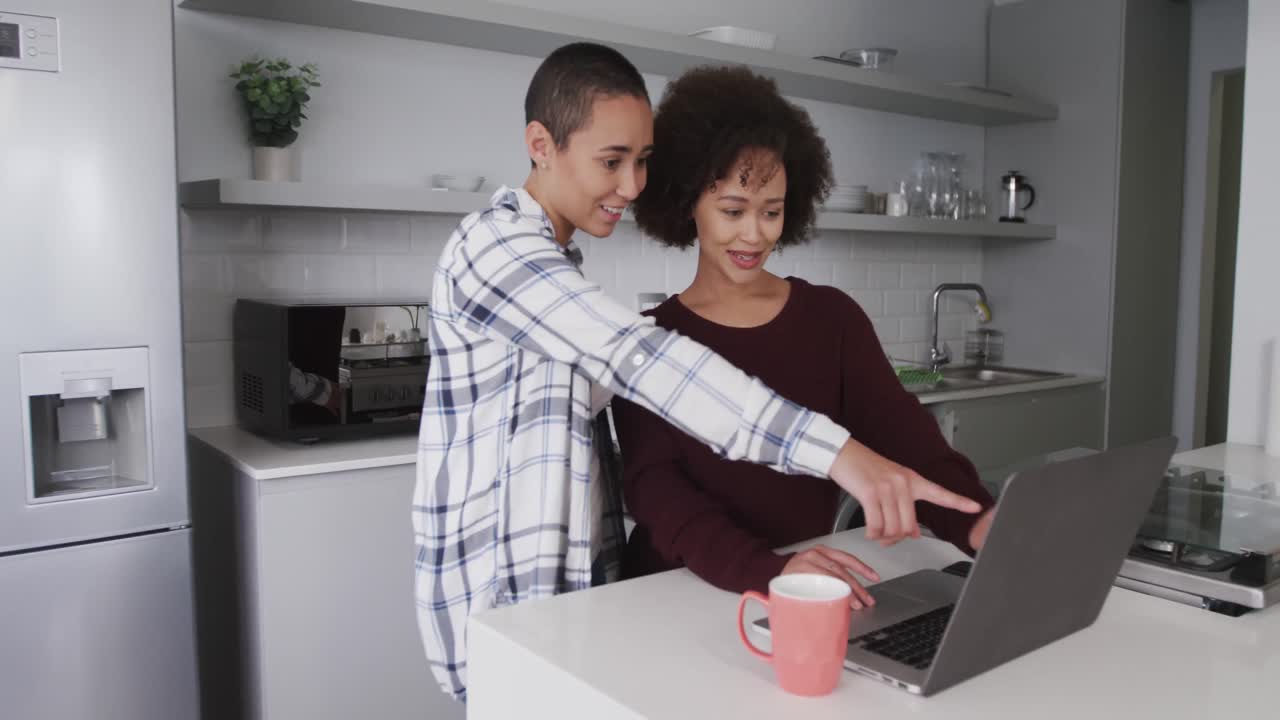 Lesbian couple using laptop in kitchen