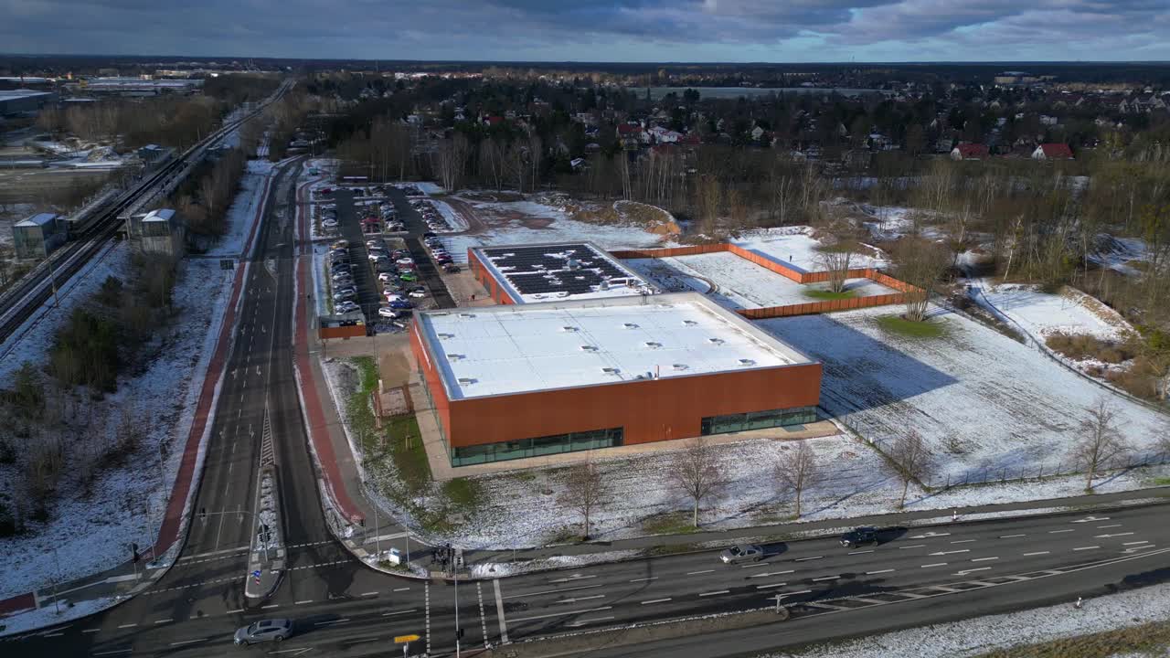 Indoor swimming pool with solar panels surrounded by snow and suburban homes in Falkensee Germany. Majestic aerial view flight drone shot footage from above