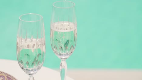 two cup glass of white wine champagne on a table with swimming pool clear water on background