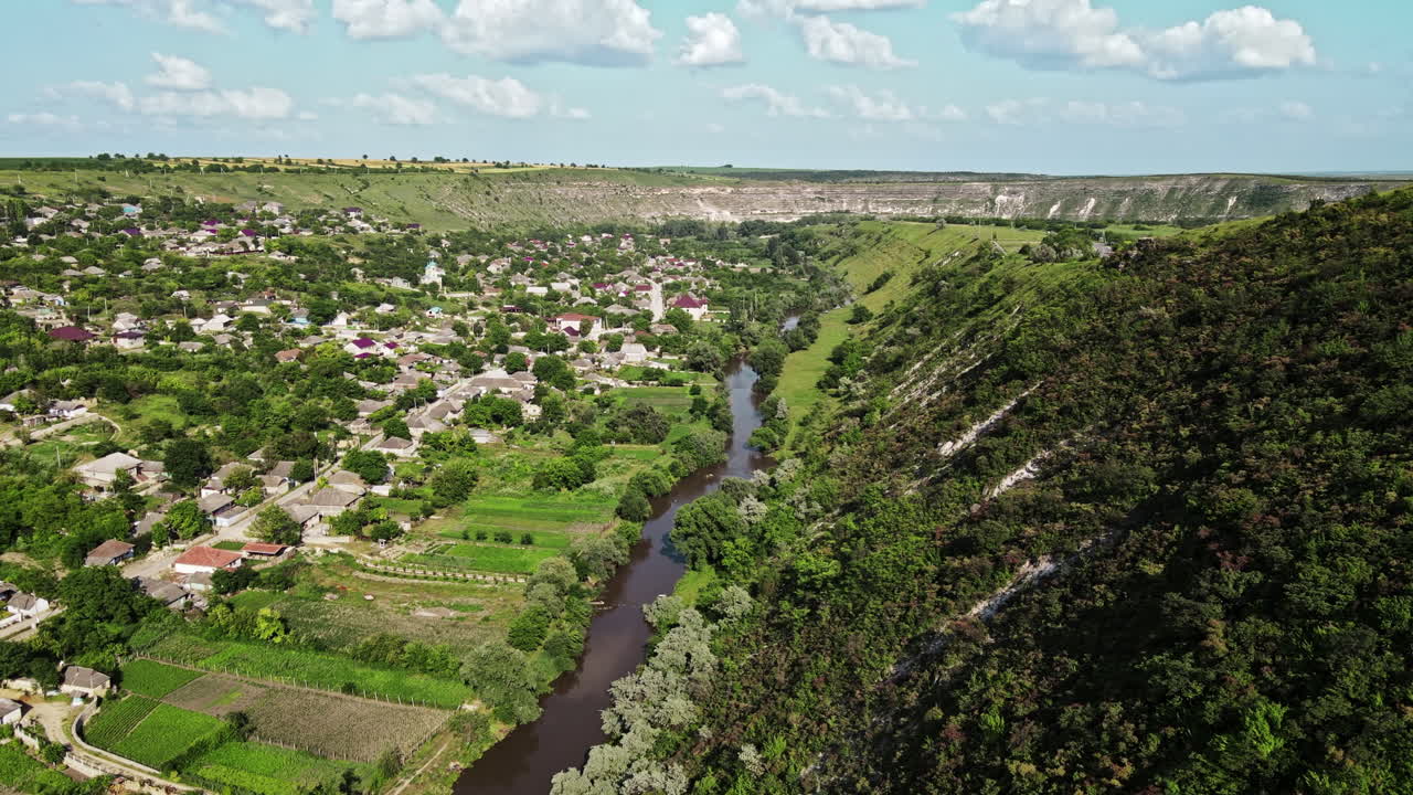 Aerial drone view of nature, valley with river and village, hills and fields, greenery, Moldova