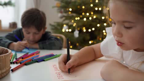 writing letter to santa claus by cute little girl with her brother