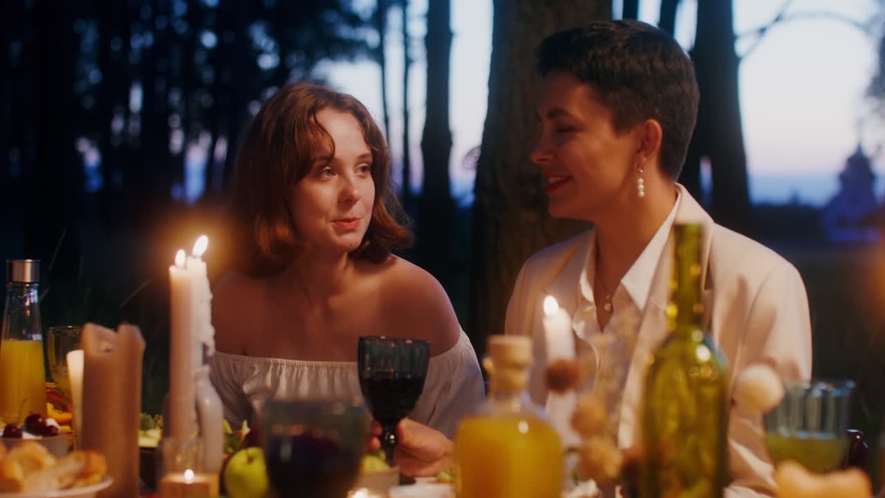 두 여인이 밤에 숲에서 만적인 저녁을 즐기고 있습니다.