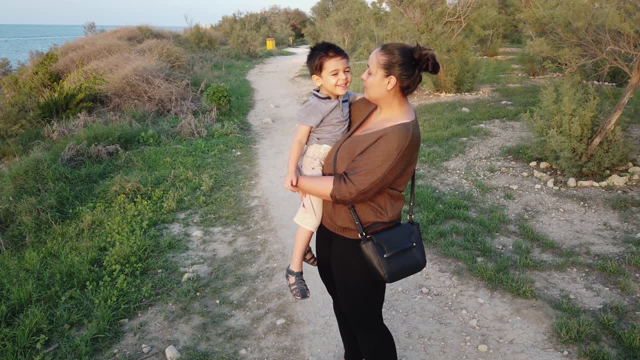 Young mother holding her 4 year old son and kissing him. Autumn on the seacoast