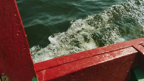 the view over the side of a row boat as it cuts through the water