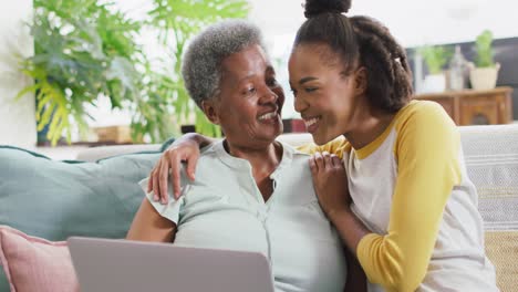 Afroamerikanische-Mutter-Und-Tochter-Lächeln,-Während-Sie-Zu-Hause-Gemeinsam-Einen-Laptop-Benutzen