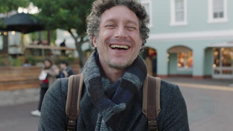 slow motion portrait of attractive mature caucasian man laughing cheerful at camera wearing scarf in urban background