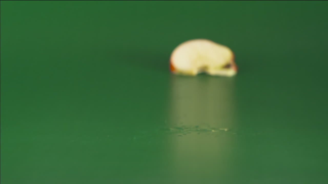 Red apple falling and breaking into pieces on a green background