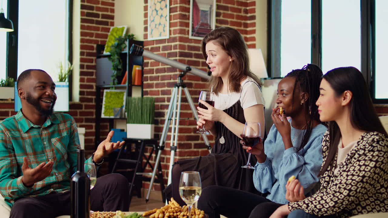 Best friends having fun together, enjoying alcohol beverages and eating crackers in cozy apartment