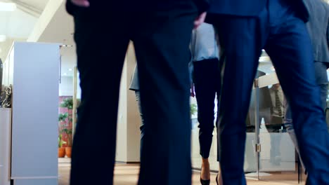 low angle shot of the business people walking through the corporate building hallway. multicultural crowd of businessmen and businesswomen busily going about their business.