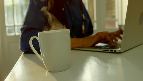 primer plano del vapor que sale de la taza de café en la mesa de comedor en la cocina de una casa cómoda 4k