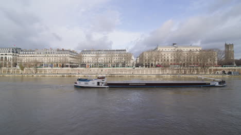 Breites-Statisches-Seitenprofil-Filmmaterial-Eines-Lastkahns,-Der-Sich-Im-Winter-Langsam-Gegen-Die-Strömung-Der-Seine-Durch-Paris-Bewegt