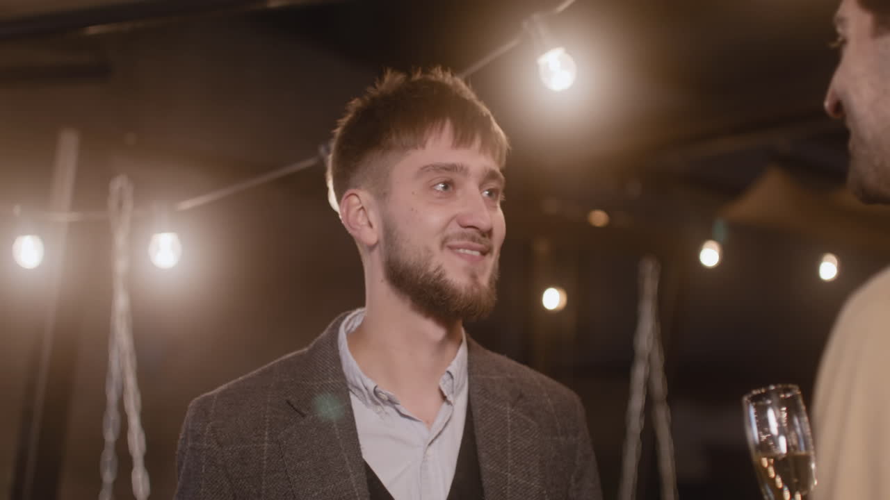 dos hombres elegantes sosteniendo copas de champán y hablando entre ellos en la fiesta de fin de año