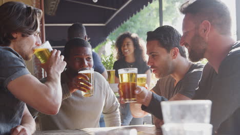 group of male friends meeting in sports bar making toast together