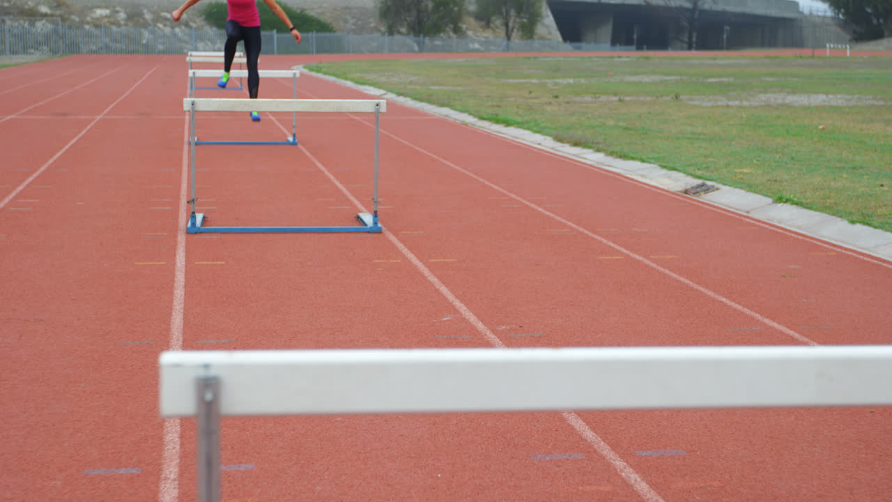 atleta caucásica que corre sobre obstáculos en una pista de atletismo en un lugar deportivo 4k
