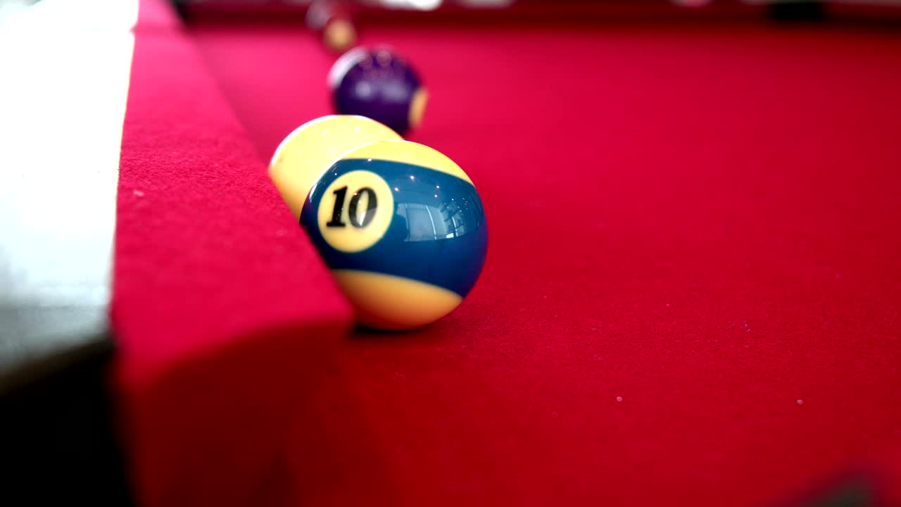 Playing the pool-billiard game on red baize table. This is sports