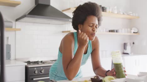 Happy-african-american-woman-preparing-healthy-drink-in-kitchen