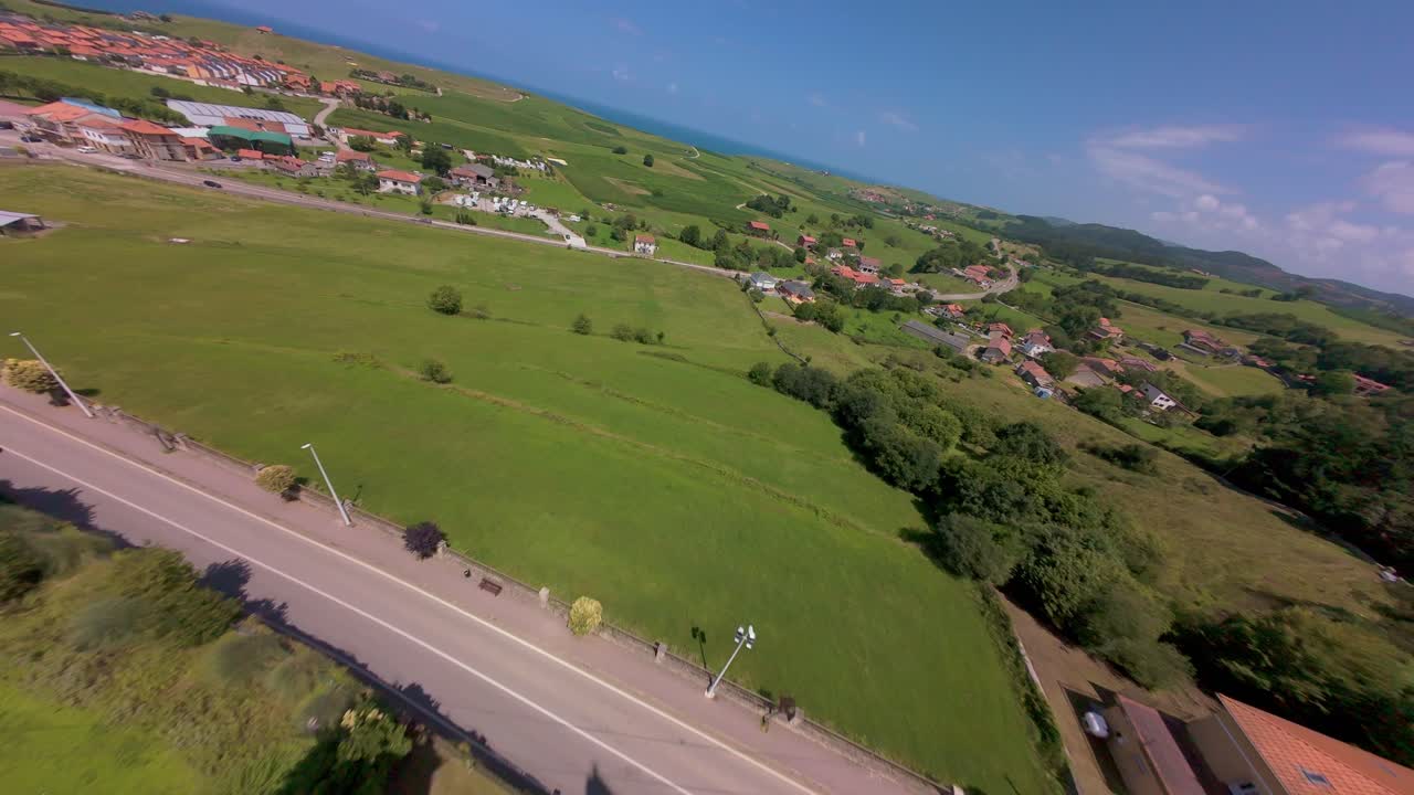 Smooth descending flythrough from a distance, flying between the twin towers of the church, with the Cantabrian sea and green meadows visible in the background