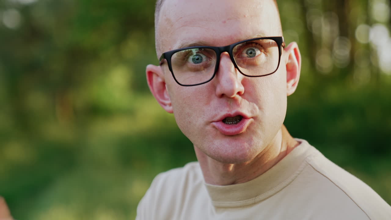 Caucasian man wearing eyeglasses works outdoors. Male freelancer talks to camera gesturing with hand.