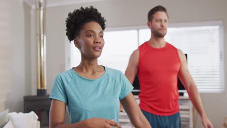 video of focused diverse couple training together at home, stretching