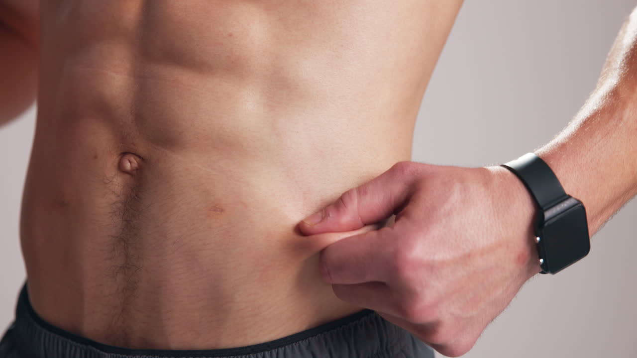 Close-up of Man Pinching Skin on His Abdomen to Check Body Fat