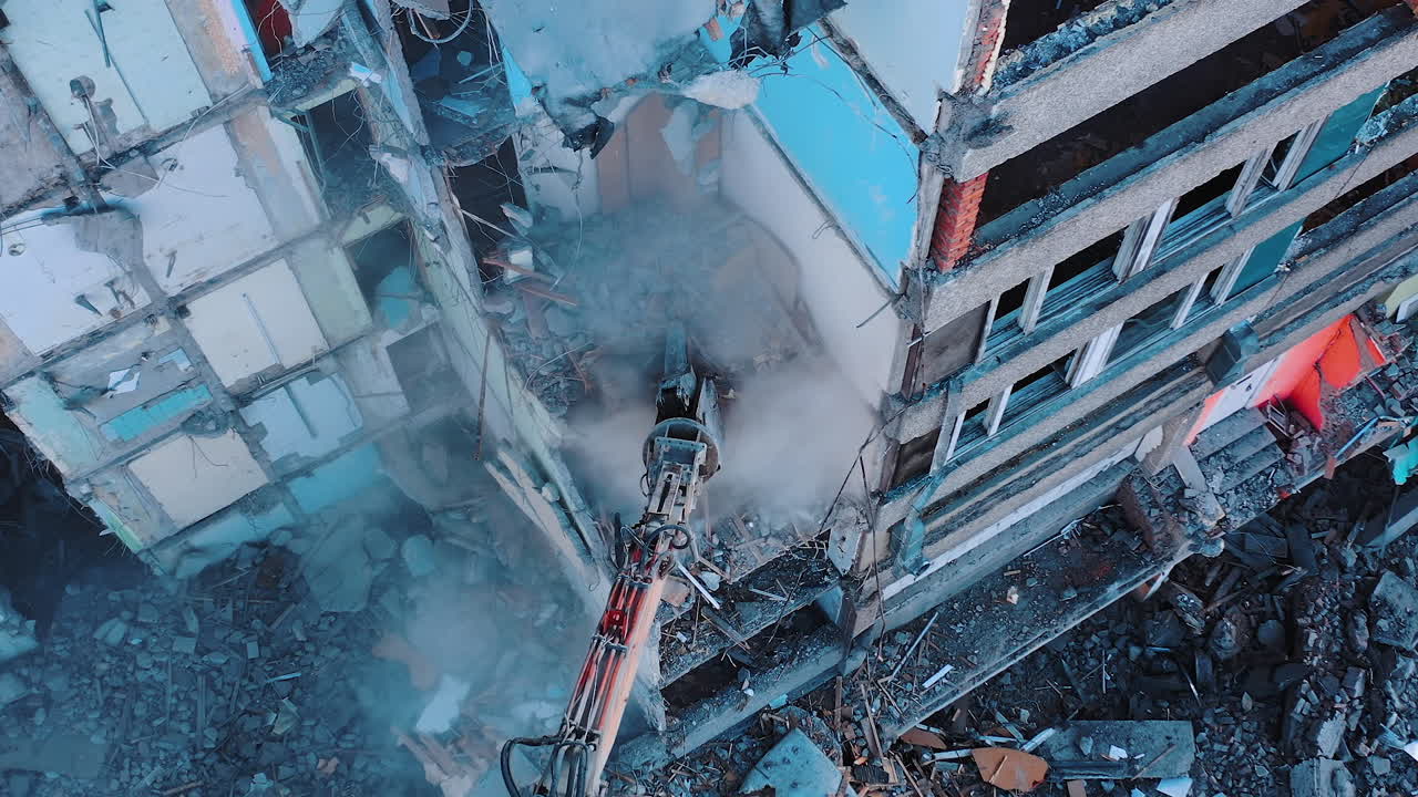 Process of dismantling a structure after an earthquake. Destruction of walls and concrete blocks that were broken by the earthquake. Excavator dismantling high buildings.