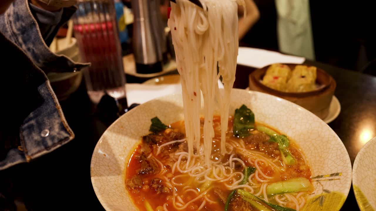 persona comiendo fideos con palillos en un restaurante de melbourne