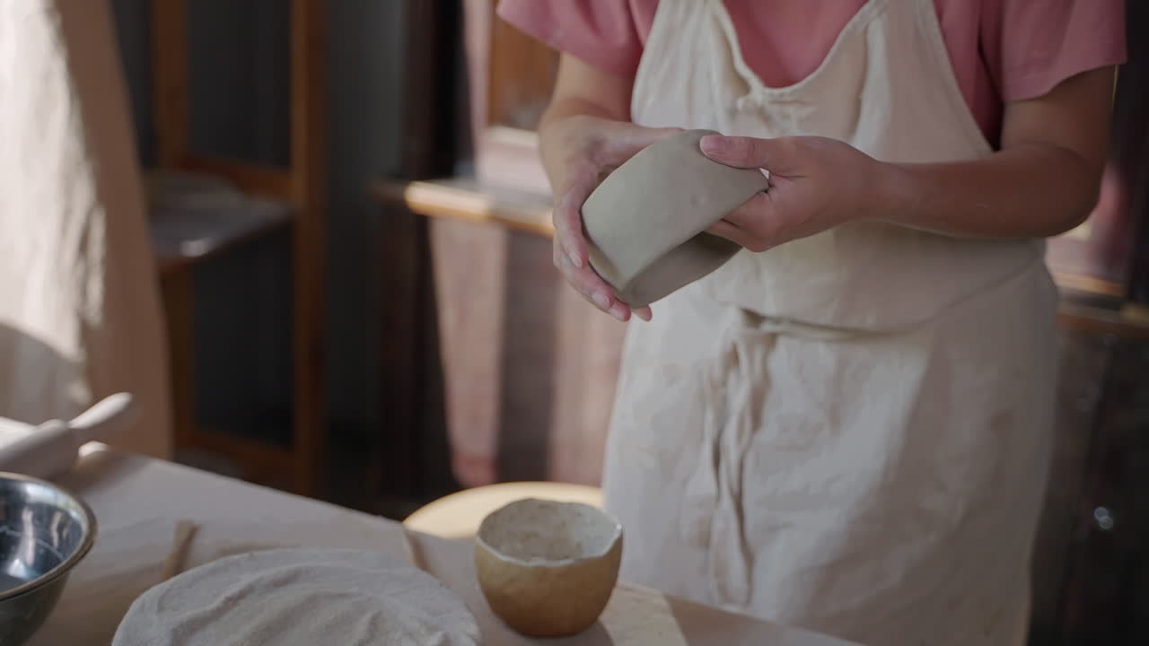женщина формирует глиняную миску в керамической студии