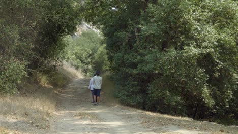 Eine-Blindenschriftlehrerin-Hilft-Einer-Blinden-Schülerin,-Ihren-Weißen-Stock-Zu-Benutzen,-Um-Auf-Einer-Unbefestigten-Straße-Im-Kalifornischen-Wald-Zu-Gehen