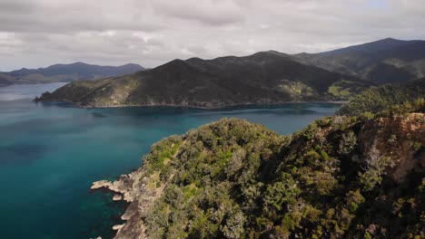 Fly-over-rocky-mountain-and-rainforest-at-Coromandel-seaside,-New-Zealand