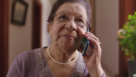 portrait of elegant elderly mixed race woman chatting on phone enjoying conversation wearing pearl necklace retirement home