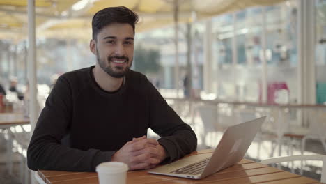 young man using laptop and smiling at camera