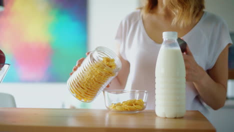 manos de mujer preparando cereales con leche en la mesa de la cocina