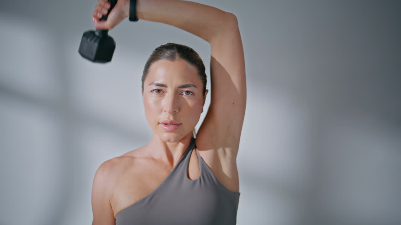 Portrait sportswoman biceps workout looking camera in fitness center studio