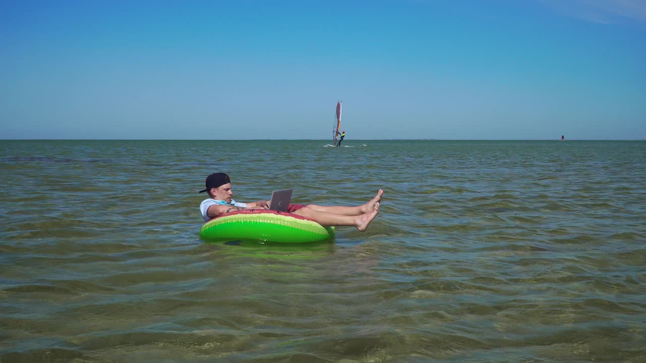 A young business person is enthusiastically working behind a laptop swaying on the waves of sea