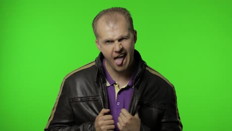 aggressive rocker man in brown leather jacket showing tongue and looking with crazy expression