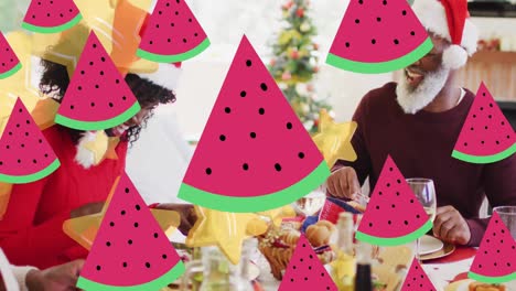 animación de estrellas sobre familia afroamericana con sombreros de papá noel teniendo la cena de navidad