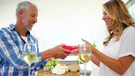 uomo maturo che dà un regalo a sorpresa alla donna mentre fa colazione
