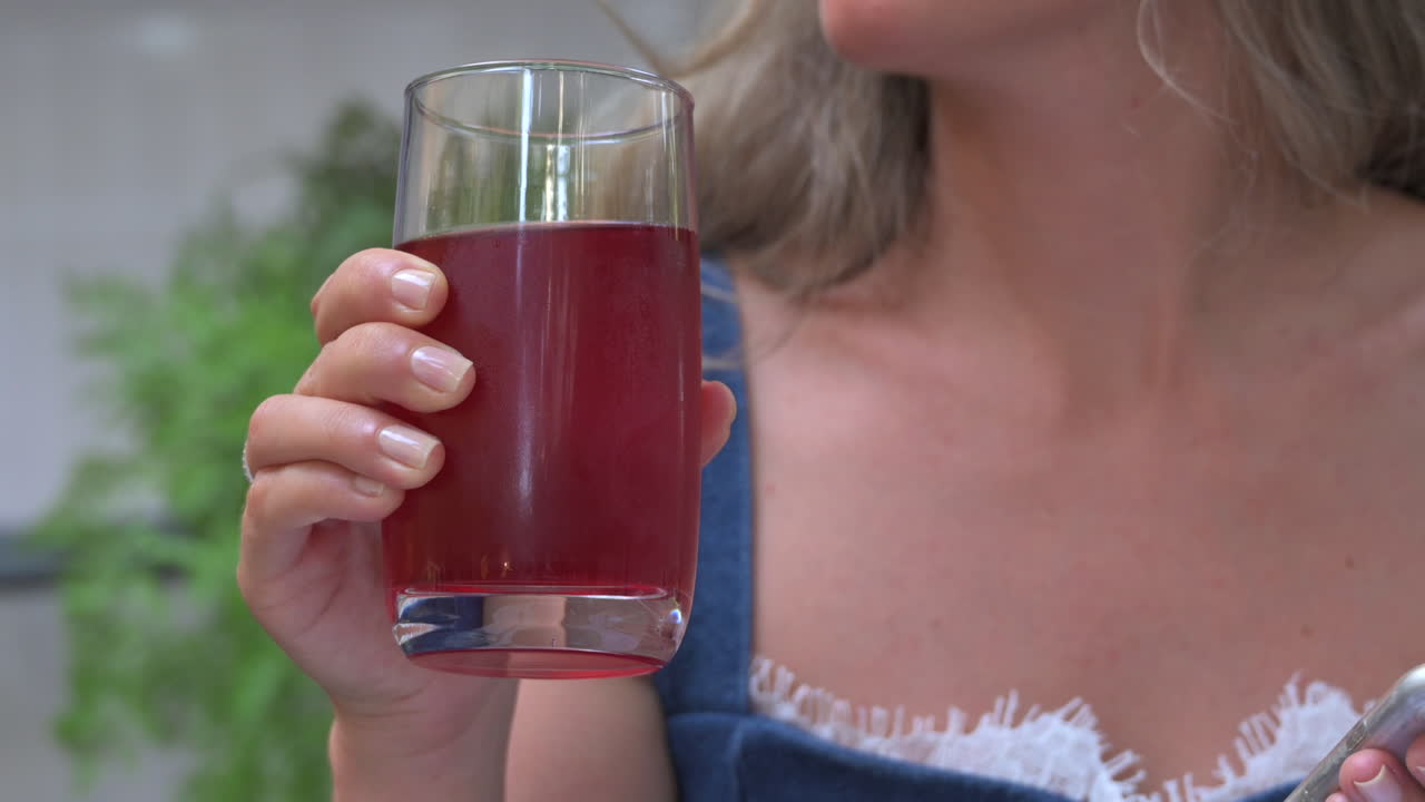 Woman drinking red juice in a glass at a restaurant