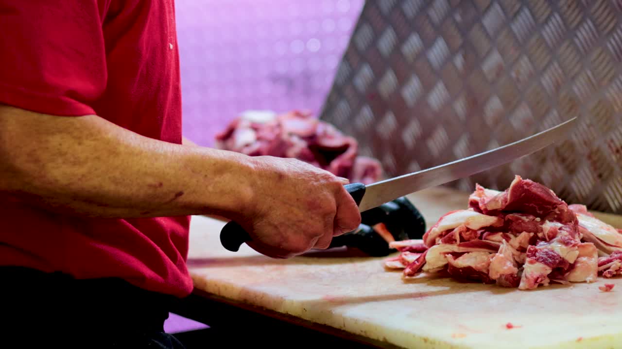 un carnicero expertamente corta carne en una tabla de madera, mostrando precisión y habilidad en una tienda de melbourne