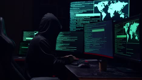 male hacker hacking with multiple computer screens in dark room